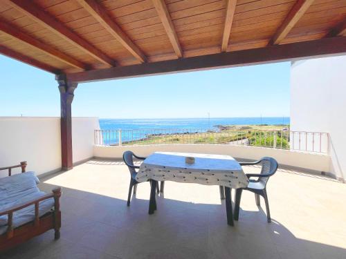 a table and chairs on a balcony with a view of the ocean at Attico Fronte Mare Salento in Torre San Giovanni Ugento