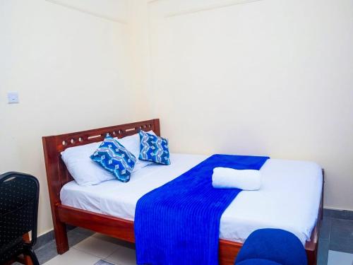 a bedroom with a bed with blue and white pillows at Dorado Homestay, Chaani in Mombasa