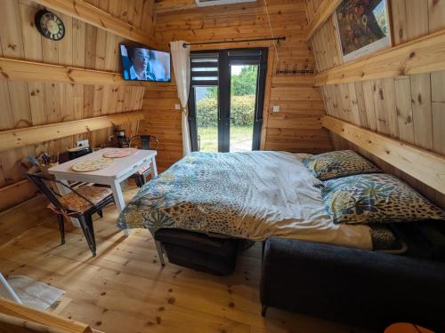 a bedroom in a log cabin with a bed and a table at Tipi Big Foot in Vivy