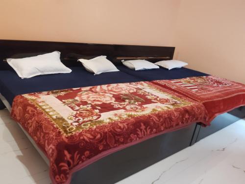 a bed with a red blanket and white pillows on it at Abhishek chand kaushik guest House in Ayodhya