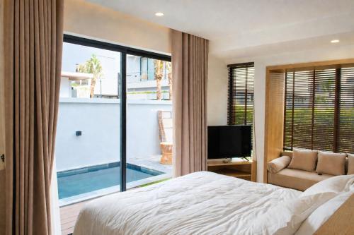 a bedroom with a bed and a tv and a pool at Sea La Vie Beachfront Villa - Bai Truong Beach Phu Quoc in Phú Quốc