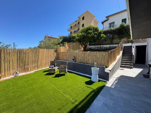a backyard with a lawn with chairs and a fence at Satori House in Sanremo