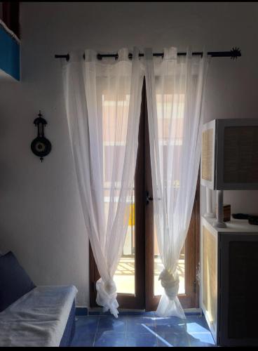a bedroom with a window with white curtains at Casa Ada - Incantevole loft in centro in Lampedusa