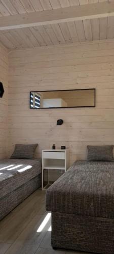 a room with two beds and a table and a mirror at Domki Amanda in Ustronie Morskie