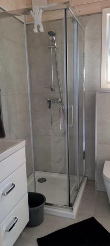 a shower with a glass door in a bathroom at Domki Amanda in Ustronie Morskie