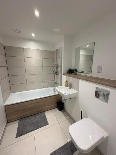 a bathroom with a tub and a toilet and a sink at Modern 2BD 2 bathroom apartment close to city centre in Manchester