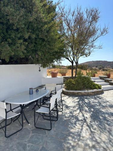 a patio with a table and chairs and trees at Cycladic Lodge Sifnos in Apollonia