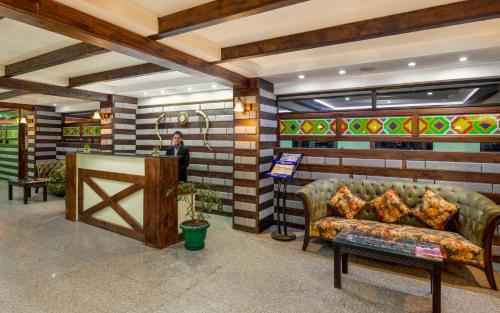 a man standing in a lobby with a couch at Shobla Royale in Kulu