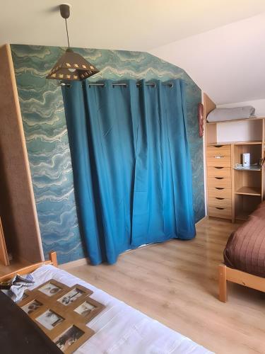 a room with a blue curtain in a bedroom at Les Orchidées - chambres d'hôtes in Surtainville