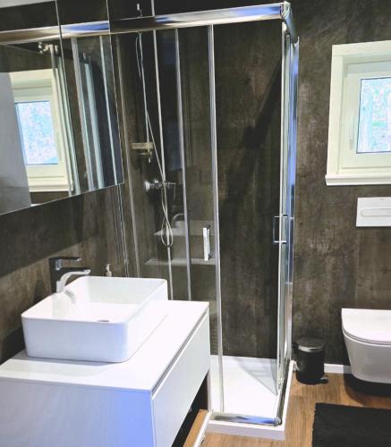 a bathroom with a white sink and a shower at Domek Leśny Potok in Sopotnia Mała