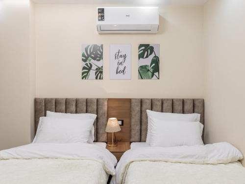two beds in a bedroom with two posters on the wall at Pool view- Luxurious 3BD Hotel Apt, Sheikh Zayed in Kafr Abū ʼumaydah