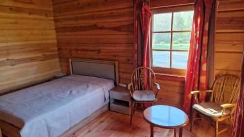 a bedroom with a bed and two chairs and a window at Aido ir Vido sodyba in Utena