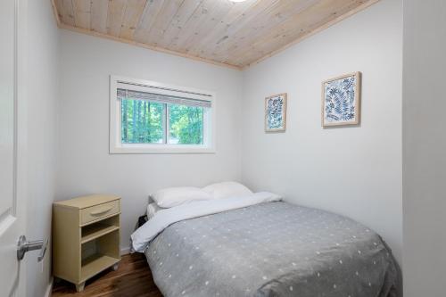 a small bedroom with a bed and a window at Diamond Lakehouse | SUP, Canoe, BBQ, Aurora Magic in Highland Grove