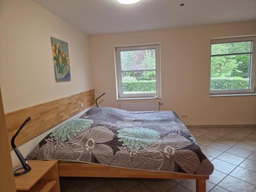 a bedroom with a bed and two windows at Gartentraum in Papenburg