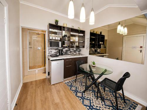 a kitchen with a glass table and black chairs at Faith, Hope & Love Self Catering in Port Elizabeth