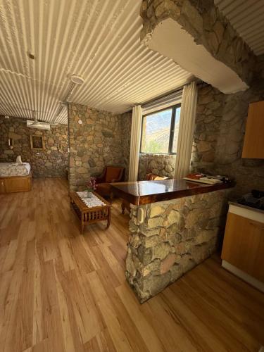 a living room with a stone wall and a table at Cabañas Caballieri in Pisco Elqui