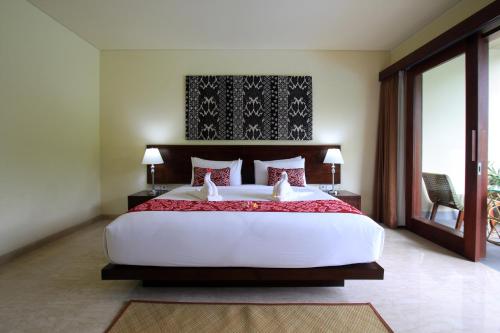 a bedroom with a large white bed with red pillows at Byasa Ubud in Ubud