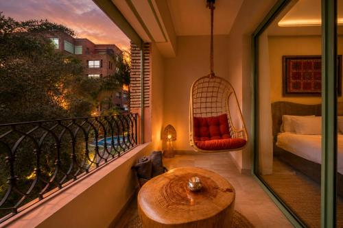 a balcony with a hammock and a bed and a table at Babylone Appart & Pool, Hivernage in Marrakesh