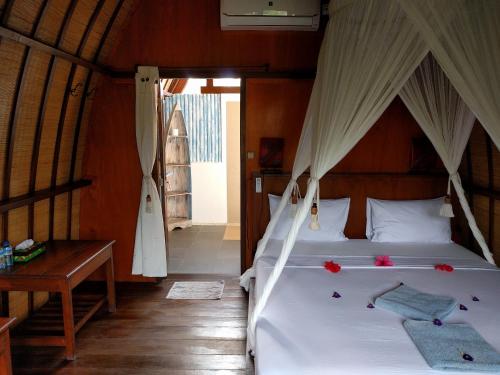 a bedroom with a bed with white sheets and flowers on it at Mango Dive & Bungalow in Gili Trawangan