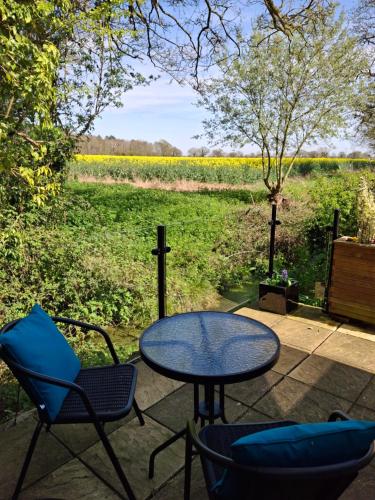 a patio with a table and chairs and a field at The Lily Pad, Eye, Suffolk in Thornham Magna