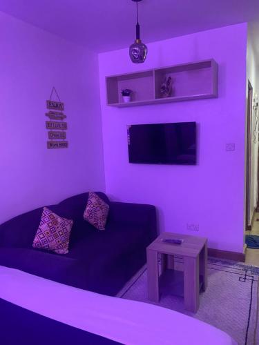 a purple living room with a couch and a table at West suites kisauni road in Nairobi