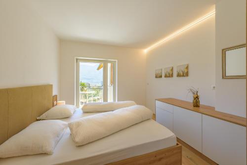 a white bedroom with two beds and a window at Ferienwohnungen Atz in Termeno