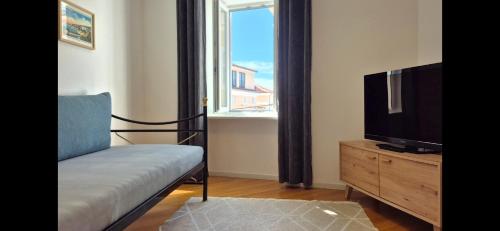 a living room with a tv and a couch and a window at Apartments San Rocco in Piran