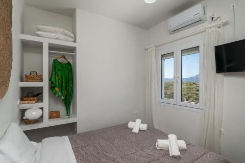 a white bedroom with a bed and a window at Artemis Cozy Home in Péran Triovasálos