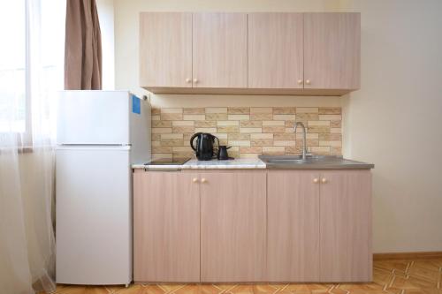 a kitchen with wooden cabinets and a white refrigerator at Soma Apart-hotel in Center in Yerevan