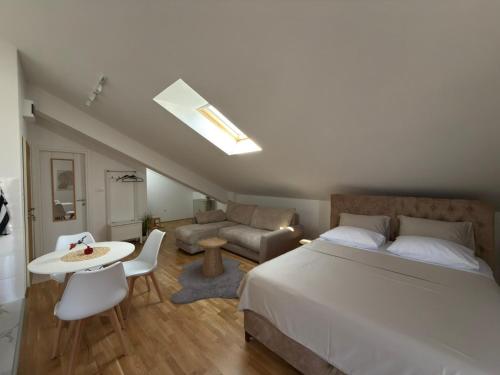 a bedroom with a bed and a table and a couch at Apartman Nadja in Podgorica