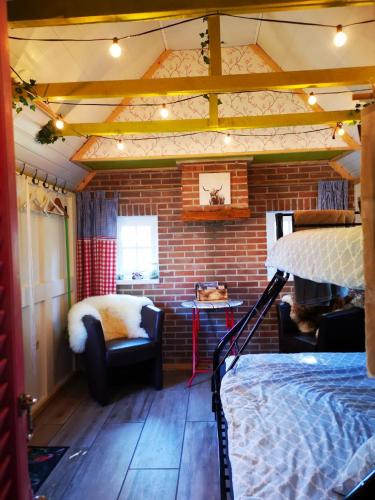 a room with a bed and a brick wall at Trekkershut - Tiny House - Hikers cottage in Wijster