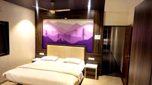 a bedroom with a bed with a painting of mountains at Vardhan Lodge in Ajra