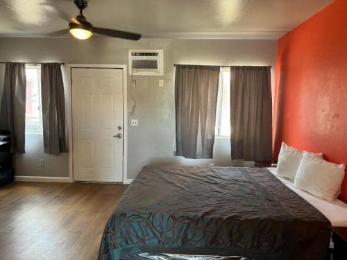 a bedroom with a bed with an orange wall at The Coalinga Motel in Coalinga