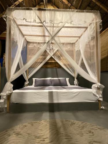 a bedroom with a canopy bed with white curtains at Foresta Yala in Tissamaharama