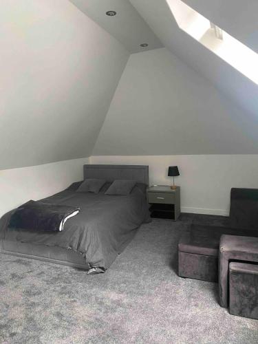a bedroom with a bed and a chair in a attic at Spacious and close to Gatwick in Crawley