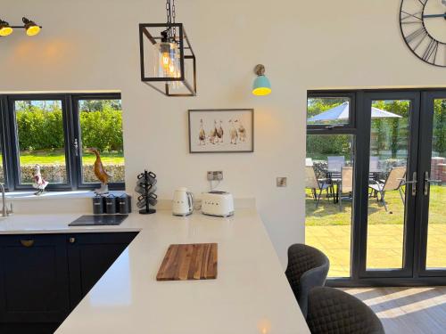 a kitchen with a white counter top and some windows at Luxury Norfolk Barn for 12 with Hot Tub , Games Room & EV Car Port in Lenwade