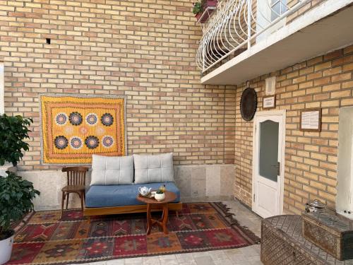 a blue couch sitting on a patio next to a brick wall at Usman Heritage in Bukhara