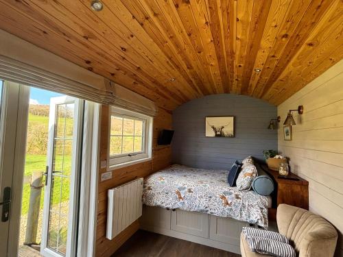 a bedroom in a tiny house with a large window at Oakies Farm Stays in Llandovery