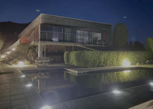 a house with a swimming pool at night at PurPlus Lodge in Vorderstoder