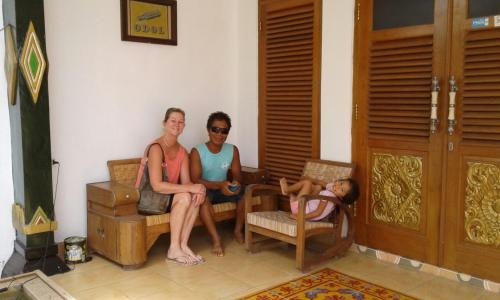 three women sitting in a room with a child laying on a chair at Rumah Desa Homestay in Prambanan