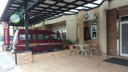 una furgoneta roja aparcada frente a un edificio con una mesa en Happy B&B, en Taitung
