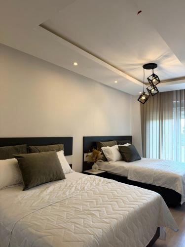 a bedroom with two beds and a chandelier at Swiss Apartments 3 in Velika Plaža