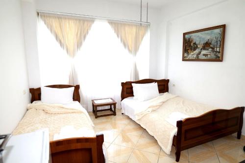 two beds in a room with a window at Villa Ekluxe in Delvinë