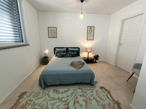 a bedroom with a bed with a blue bedspread and a rug at Funicolare 64 in Paradiso