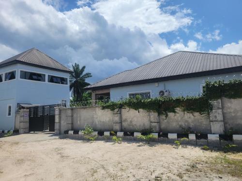 a white house with a fence in front of it at Kings Garden Inn in Ekrokpe