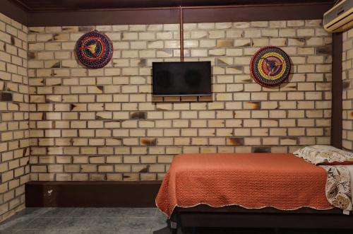 a bedroom with a bed and a tv on a brick wall at Pousada Zululand in Guarda do Embaú