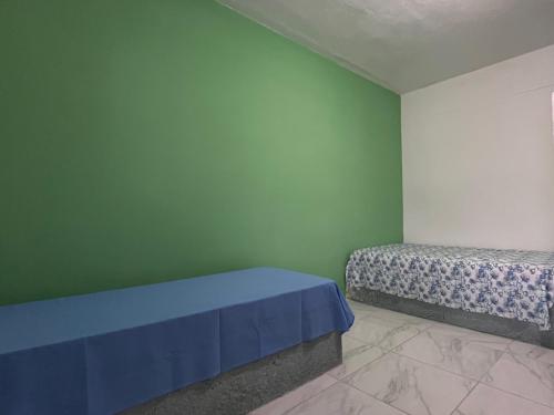 a room with two beds and a green wall at Pousada Açaí in Ilha Comprida