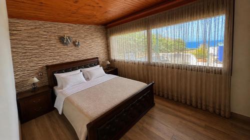 a bedroom with a bed and a large window at Ardani paradise view villa with jacuzzi in Amoopi