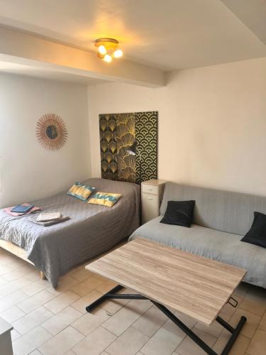 a bedroom with two beds and a table at Charmant studio au centre de Gréoux-les-Bains in Gréoux-les-Bains