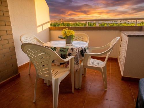 a table with chairs and a vase of flowers on a balcony at Jardines del mar III-2ª linea de playa Piscina y Parking Ideal familias Marina d'Or in El Borseral